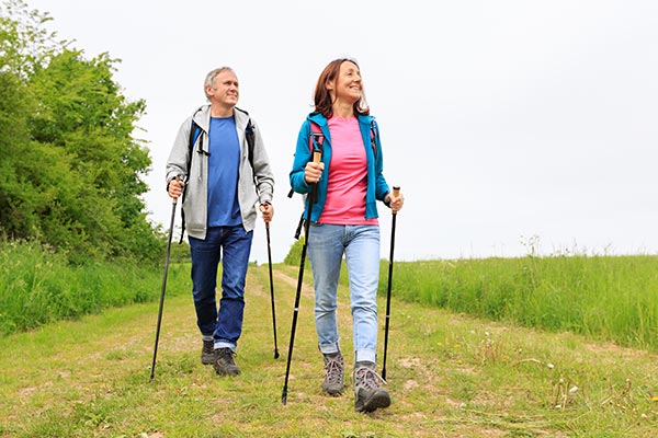 Älteres Paar in der Natur beim Nordic Walking